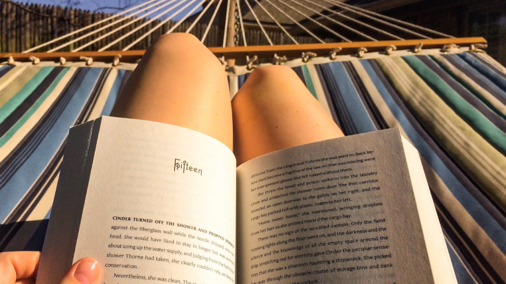 Photo of a woman reading a book from her hammock