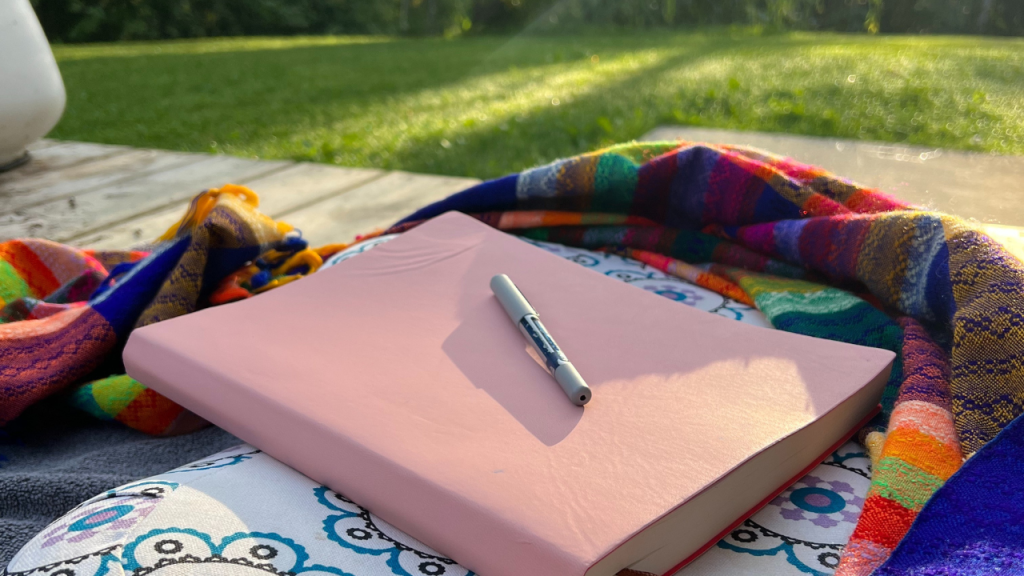 Photo of a journal on top of a meditation pillow outside in nature